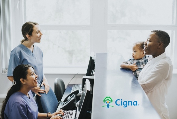 Parent and child discussing dental insurance with team members with Cigna logo in background