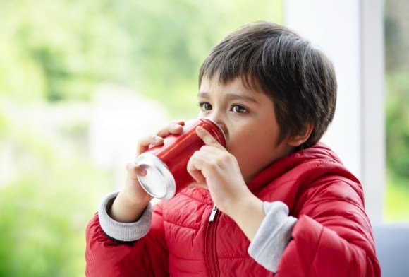 Child drinking acidic soda who may need fluoride treatment