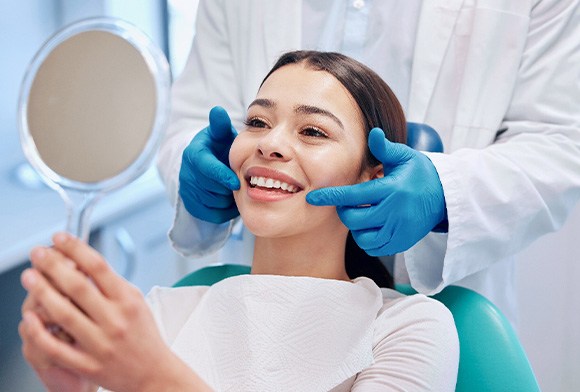 Woman smiling at reflection in handheld mirror