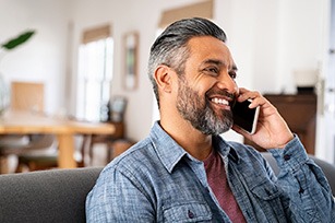 Man smiling while talking on phone at home