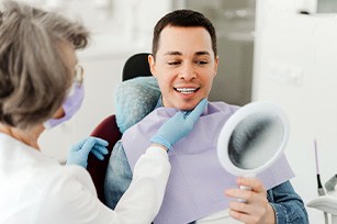 Man smiling at reflection in mirror with dentist