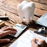 patient calculating cost of root canal on desk