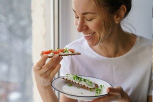 Woman smiling while eating healthy snack at home