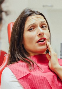 a person holding their cheek due to tooth pain