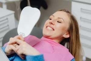 Woman looking at her teeth in a dental mirror