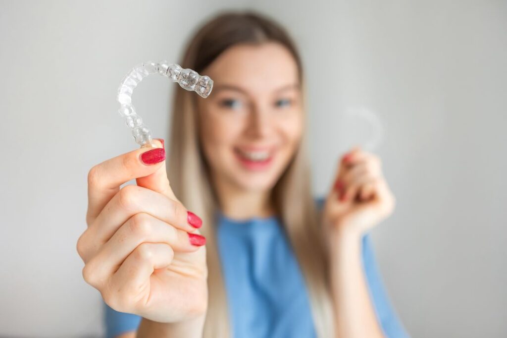 A woman holding an Invisalign aligner